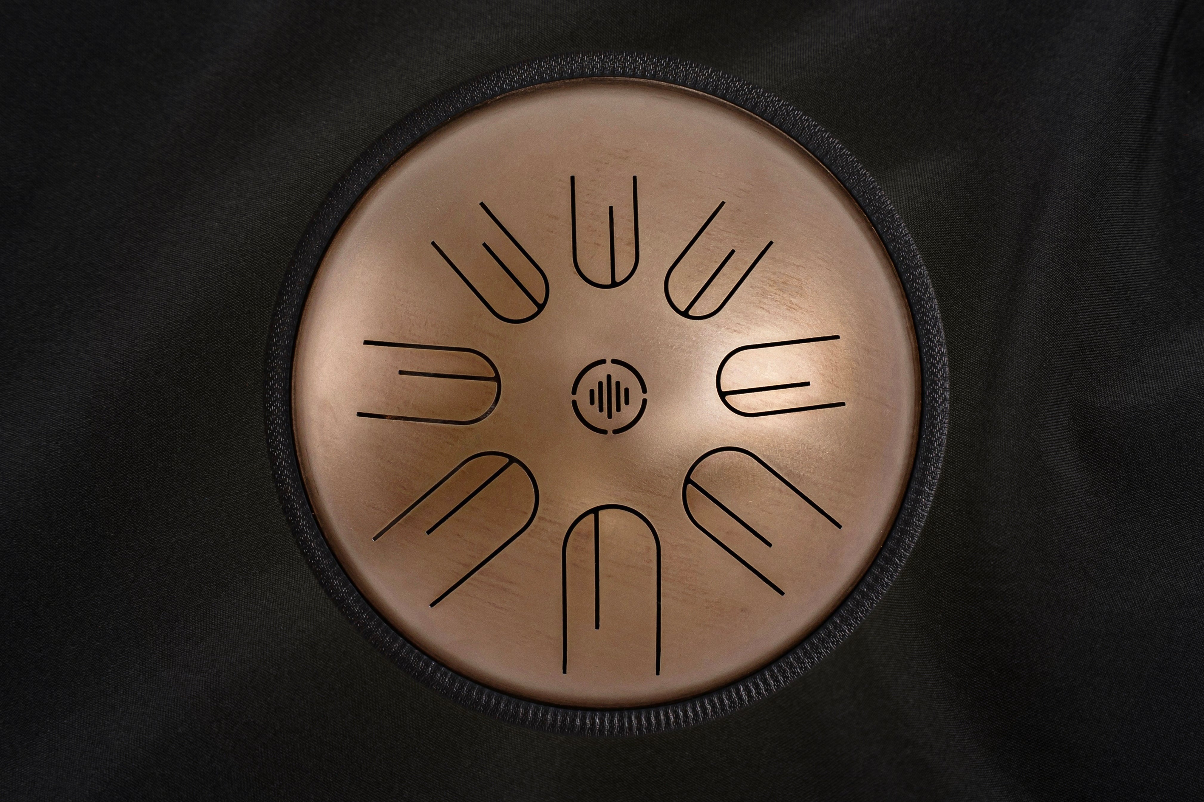 Front view of Novadrum 28 steel tongue drum in stainless steel, with precision-cut tongues arranged symmetrically around a central logo.