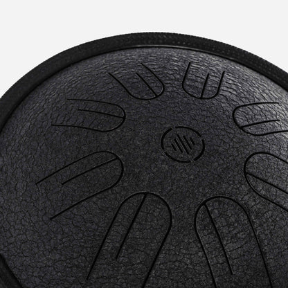 Close-up front view of Novadrum 28 steel tongue drum in black textured finish, featuring precision-cut tongues symmetrically arranged around a central logo