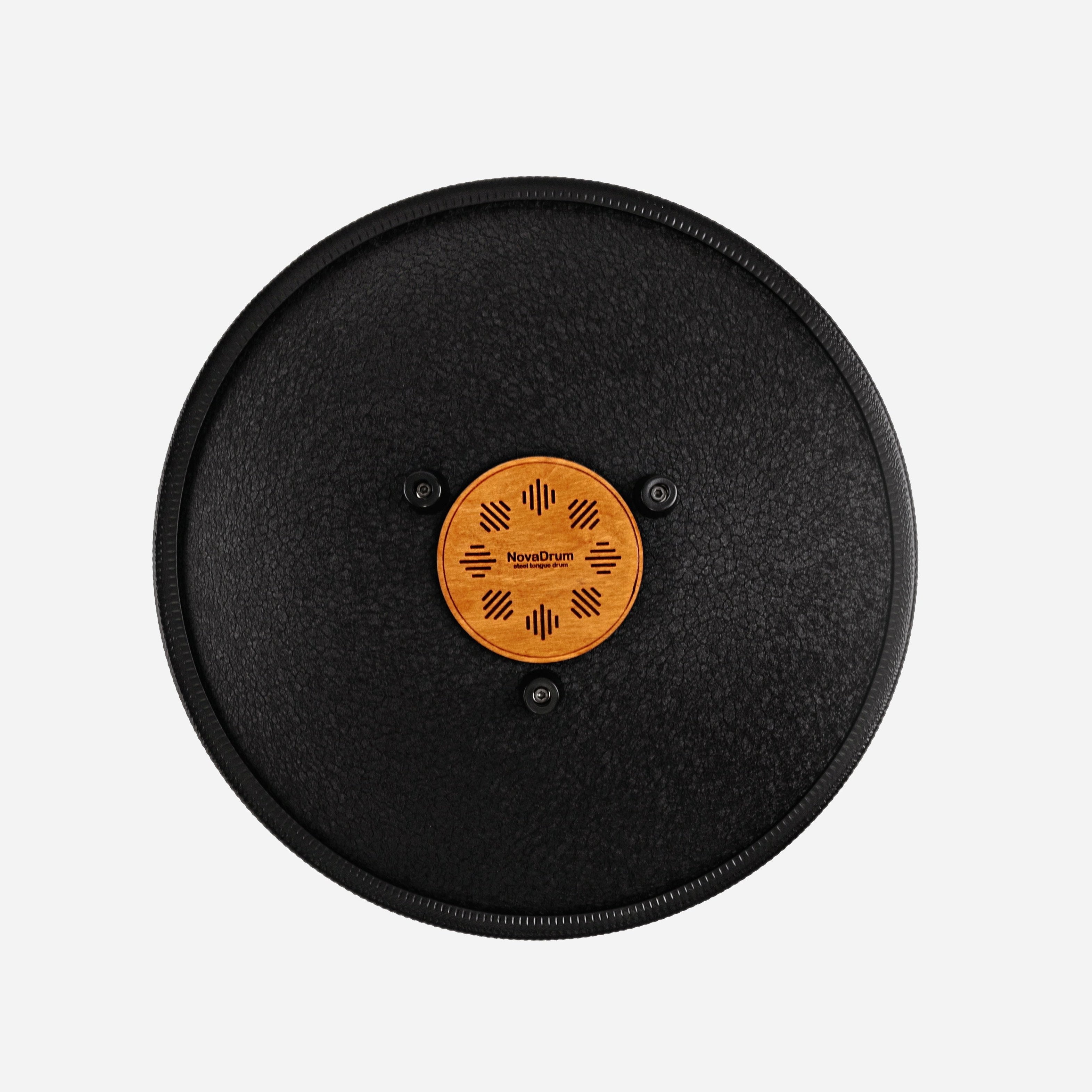 Back view of Novadrum 38 steel tongue drum in black textured finish, showing a wooden cover with engraved ‘NovaDrum’ branding, rubber feet, and black rope rim.