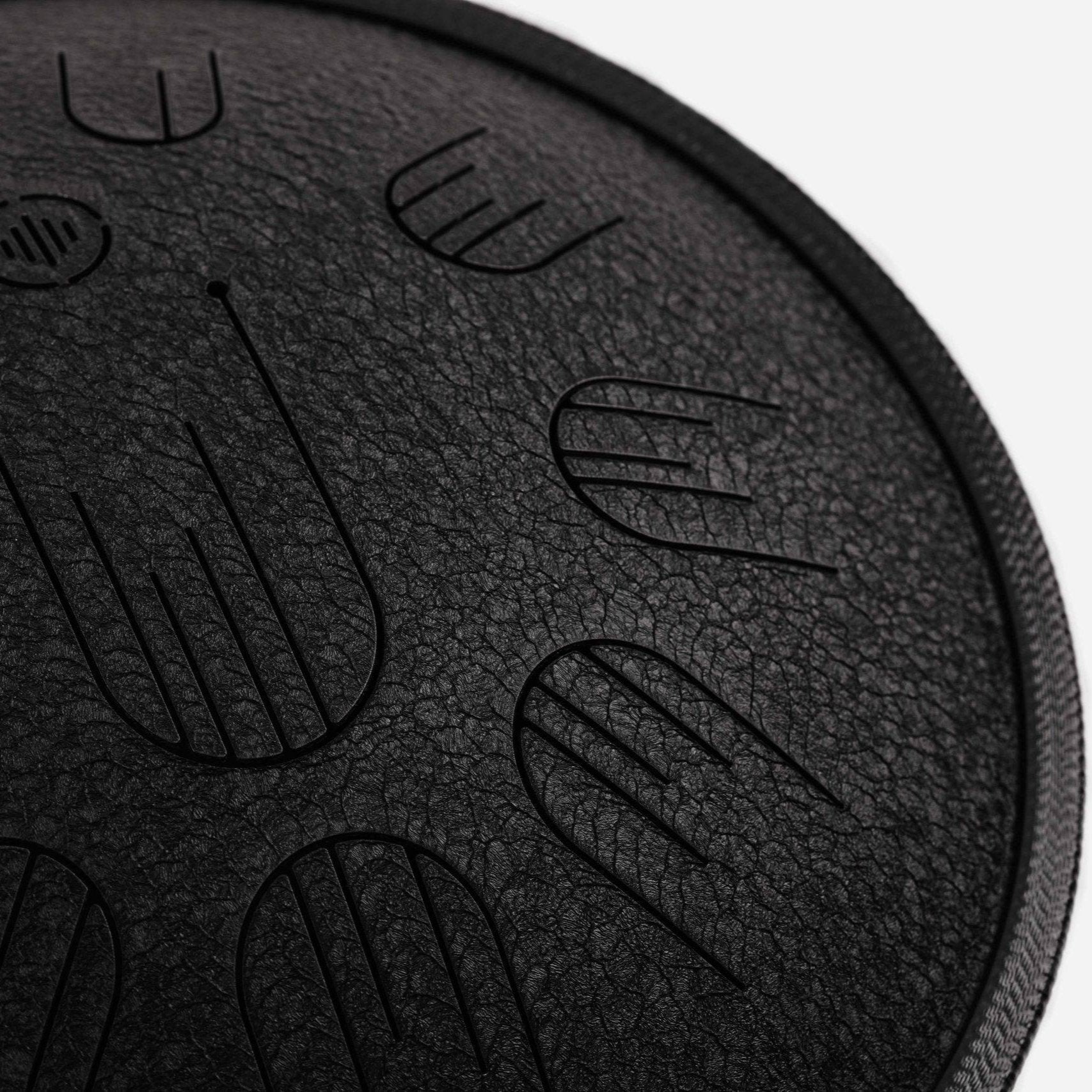 Close-up front view of Novadrum 38 steel tongue drum in black textured finish, highlighting precision-cut tongues and centered logo.