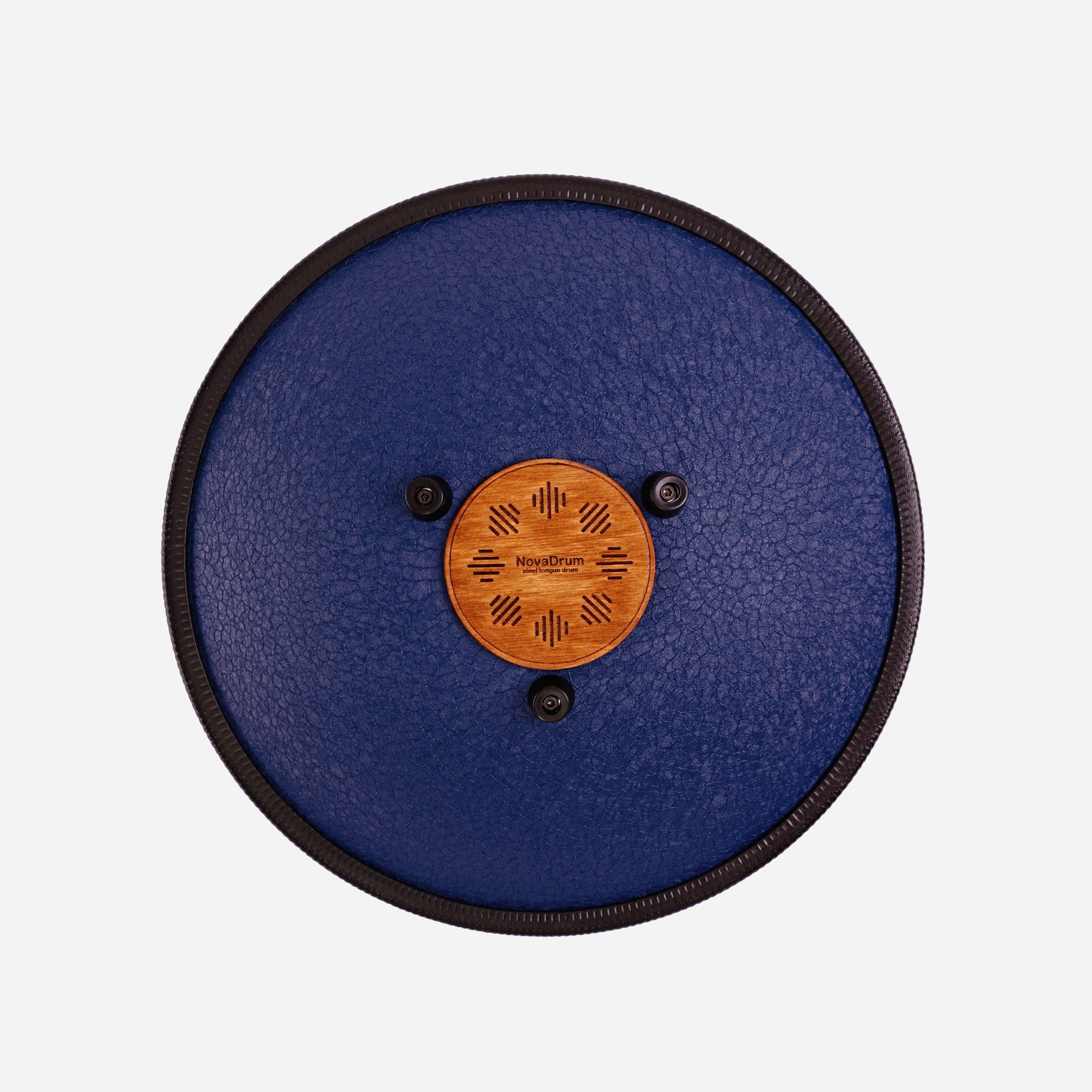 Back view of Novadrum 38 steel tongue drum in blue textured finish, showing a wooden cover with engraved ‘NovaDrum’ branding, rubber feet, and black rope rim.