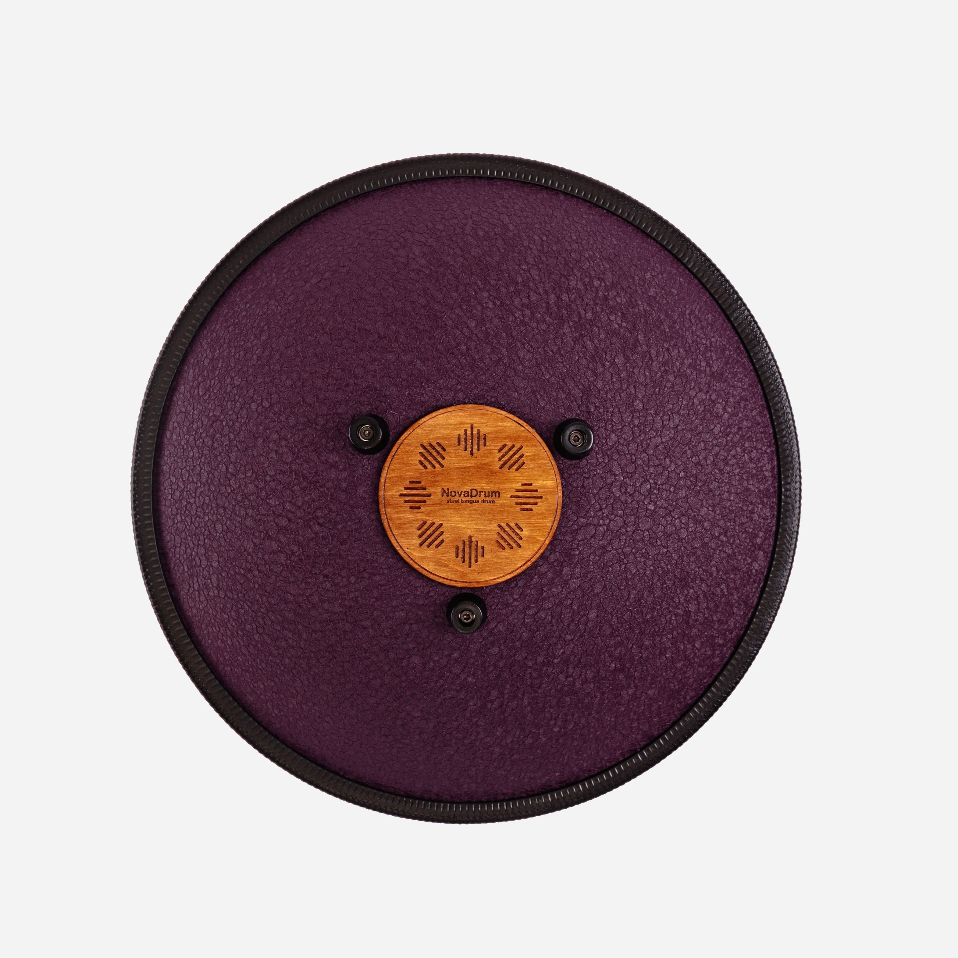 Back view of Novadrum 38 steel tongue drum in black textured finish, showing a wooden cover with engraved ‘NovaDrum’ branding, rubber feet, and black rope rim.