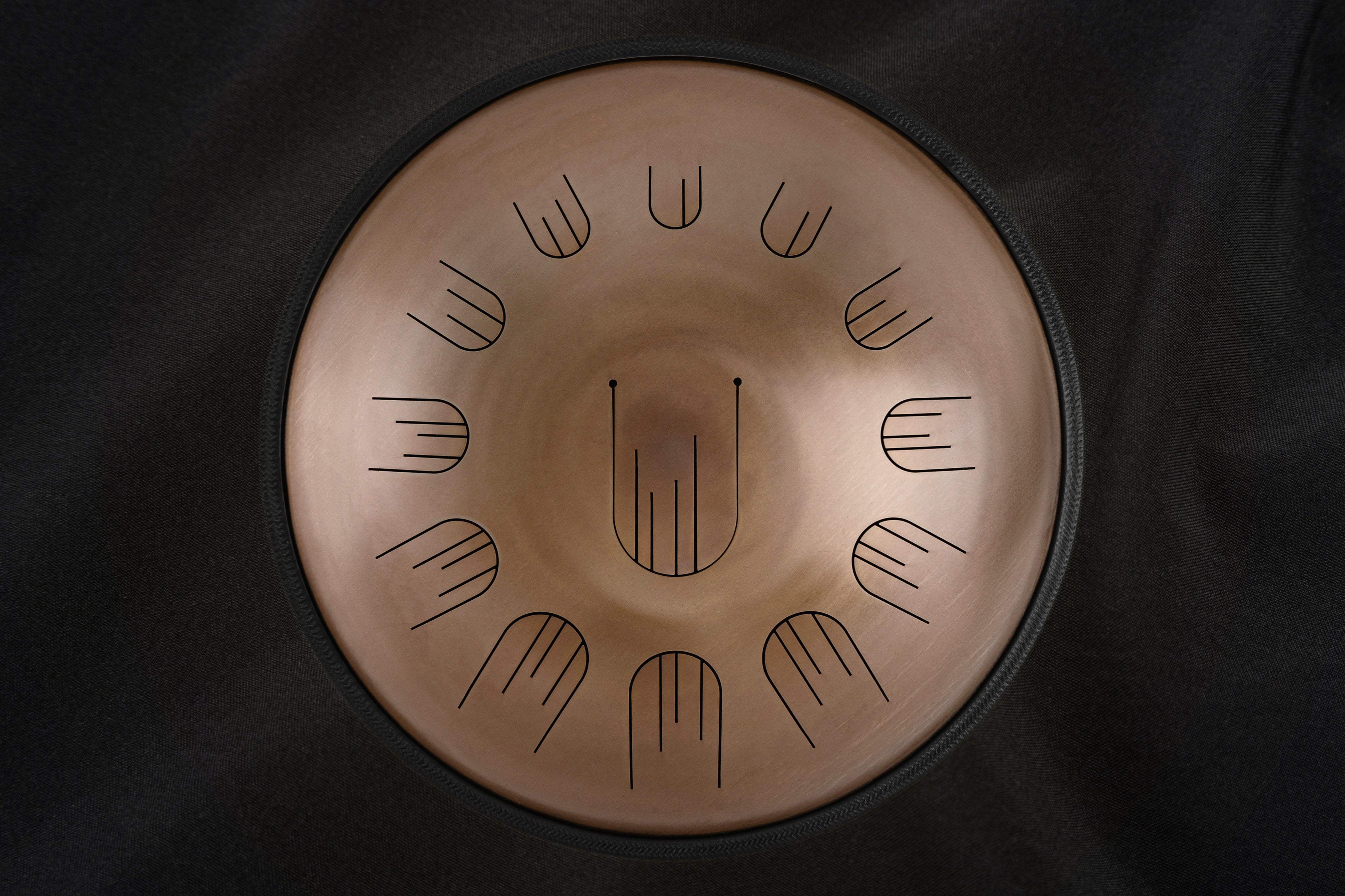 Front view of Novadrum 48 big steel tongue drum in stainless steel, with precision-cut tongues arranged symmetrically around a central logo.