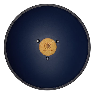 Back view of Novadrum 48 big steel tongue drum in blue matte, showing a wooden cover with engraved ‘NovaDrum’ branding, rubber feet, and black rope rim.