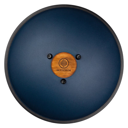 Back view of Novadrum 48 big steel tongue drum in blue matte, showing a wooden cover with engraved ‘NovaDrum’ branding, rubber feet, and black rope rim.